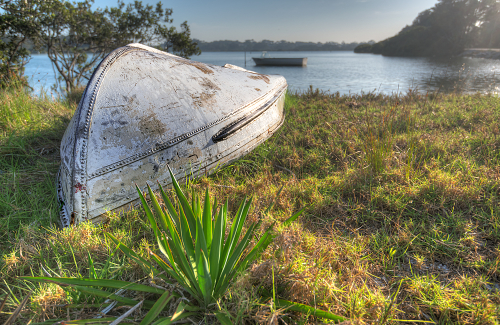 an overturned boat rests ashore at Moruya Heads, NSW, Australia